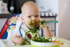 54773985-feeding-adorable-baby-child-eating-with-a-spoon-in-high-chair-baby-s-first-solid-food.jpg